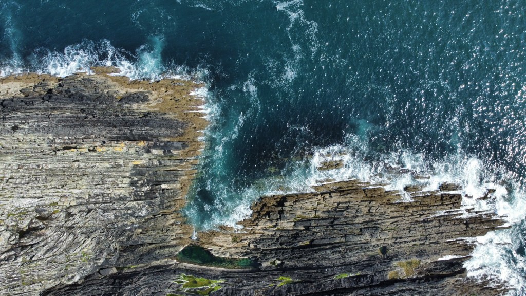 Drohnenfoto der steilen Felsklippen an der Küste von West Cork am Wild Atlantic Way in Irland mit Atlantik-Wellen.