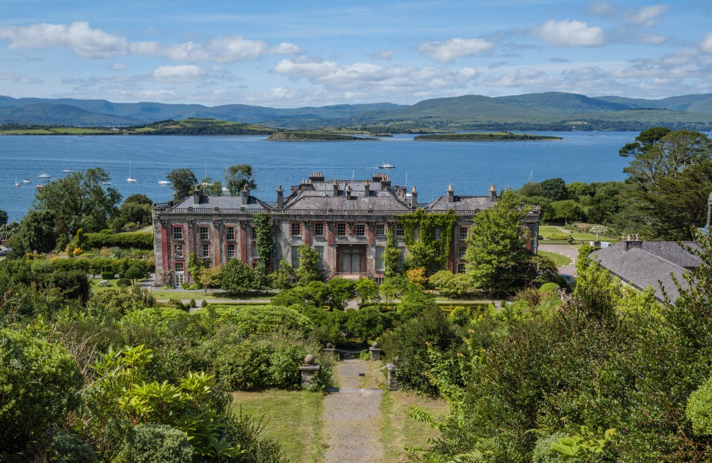 Postkarten-Ansicht von Bantry House und Garden in County Cork mit Blick über die terrassierten Gärten auf die Bantry Bay in Irland.